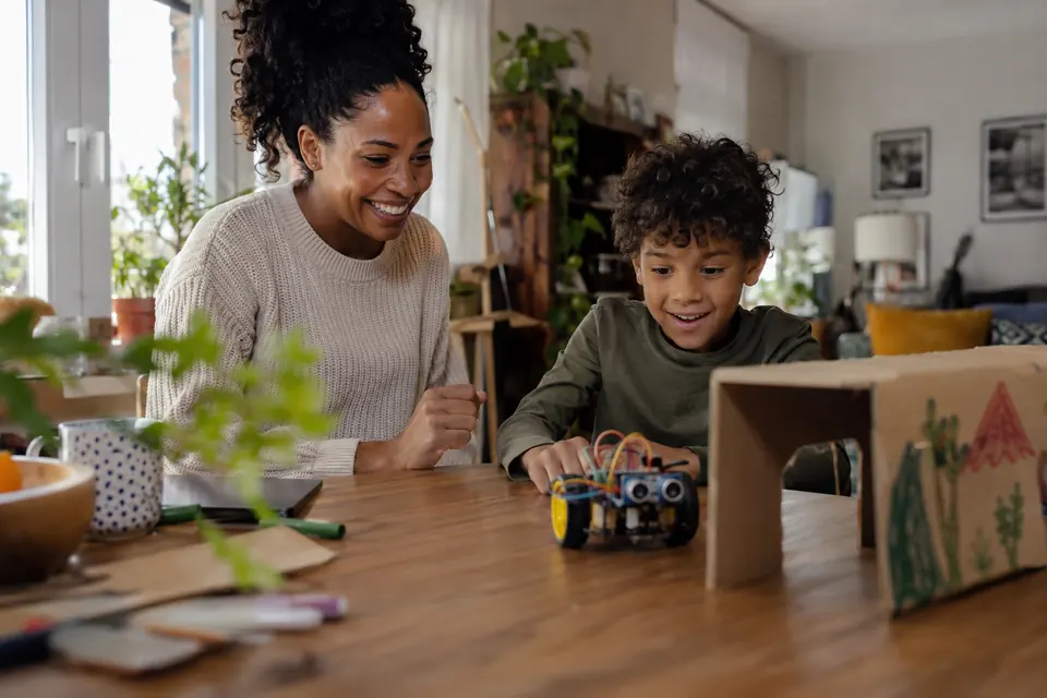 Una madre y su hijo observan un robot ante un túnel de cartón.