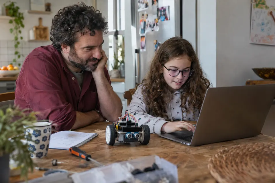 Un padre y su hija exploran la programación de un robot en un ordenador.